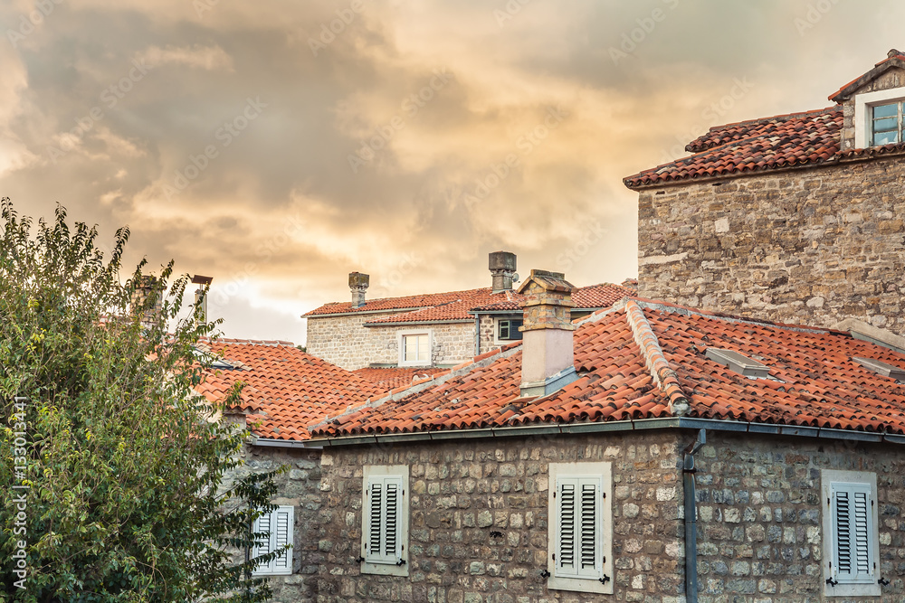 Old town orange tile roofs with old historical building facades during sunset in retro vintage style