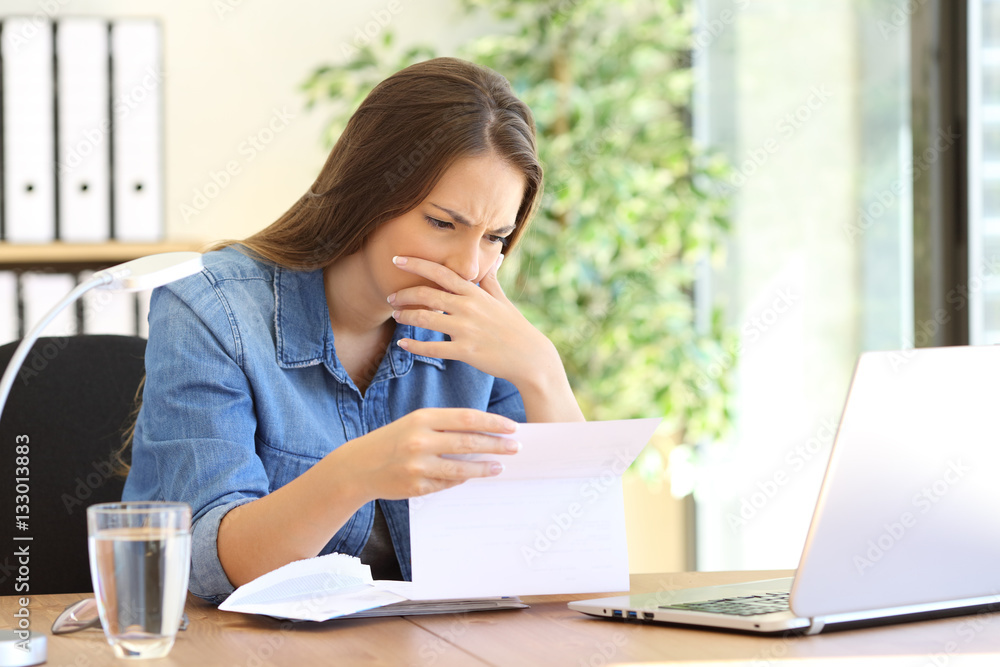 Worried entrepreneur girl reading a letter Worried entrepreneur girl reading a letter