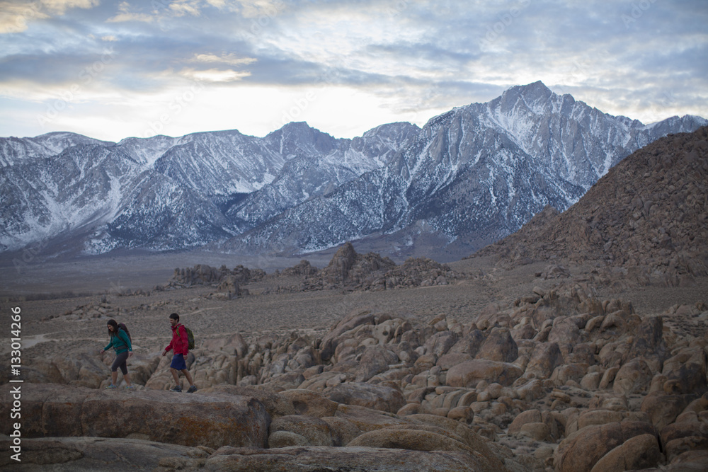 A couple  hiking in the Alabama Hills at the foot of the Sierra Nevada Mountains near Lone Pine, California.