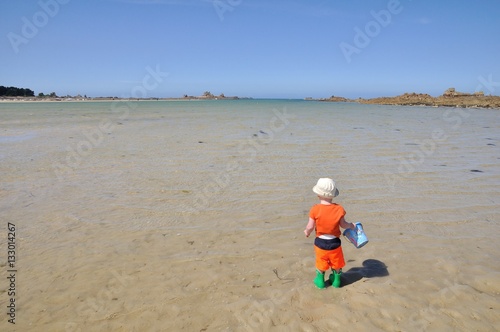 Un très jeune enfant seul face à la mer à marée basse en Bretagne