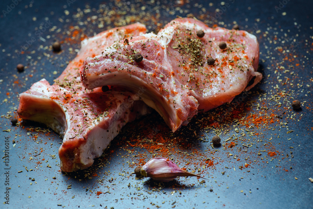 Top view raw pork chop steak and garlic, pepper, salt on wooden background.