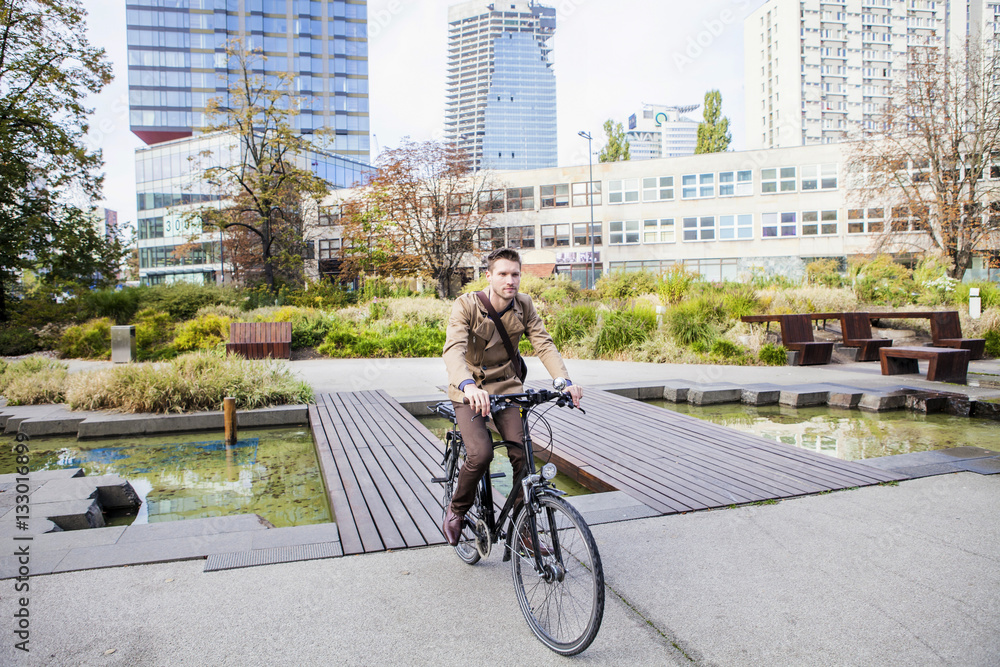Commuter riding bicycle over footbridge in park Commuter riding bicycle over footbridge in park