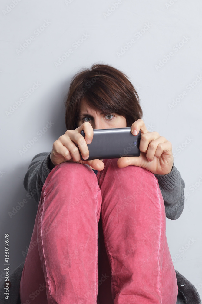 girl sitting against a wall and holding a smart phone, covering girl sitting against a wall and holding a smart phone, covering
