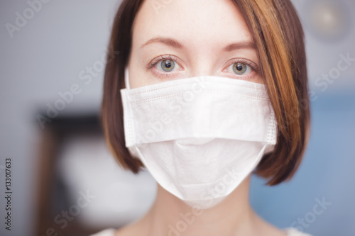 Girl in medical disposable mask looking at the camera. 