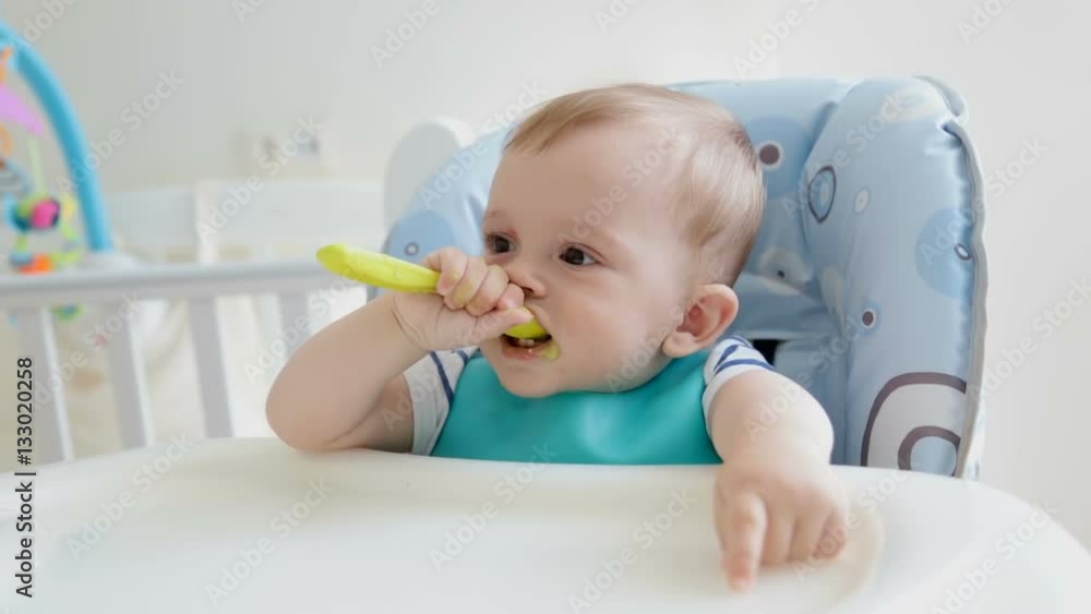 Cute baby boy playing with spoon while eating porridge