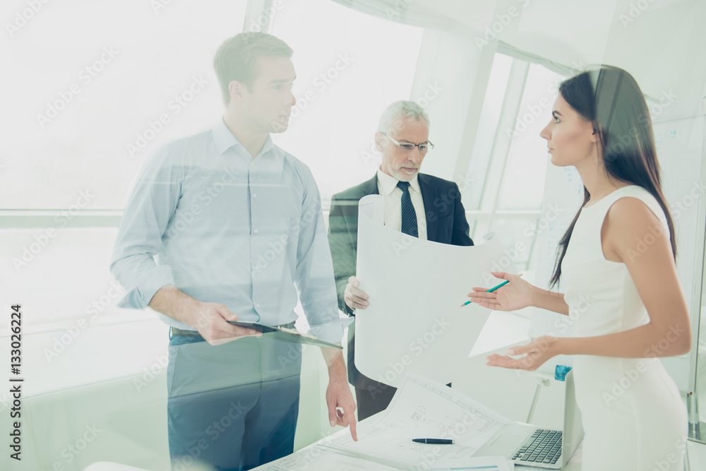 Obraz premium Team of architects holding blueprint and discussing new project