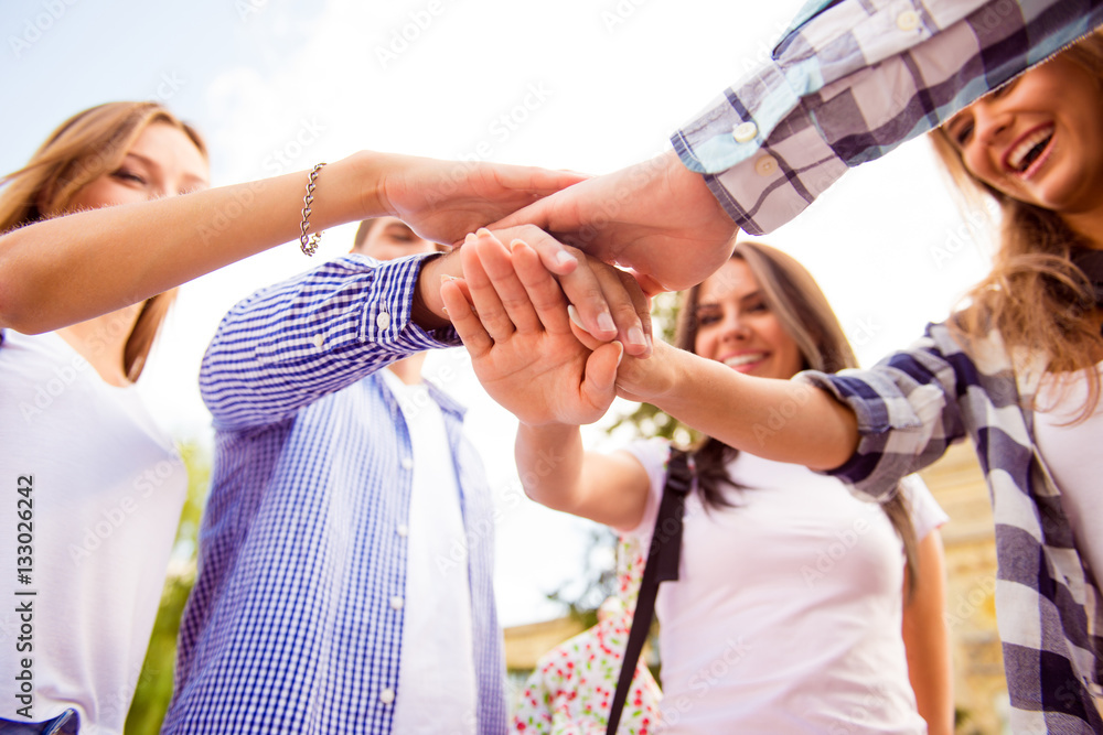 Fototapeta premium Close up photo of young friends putting their hands on top of ea