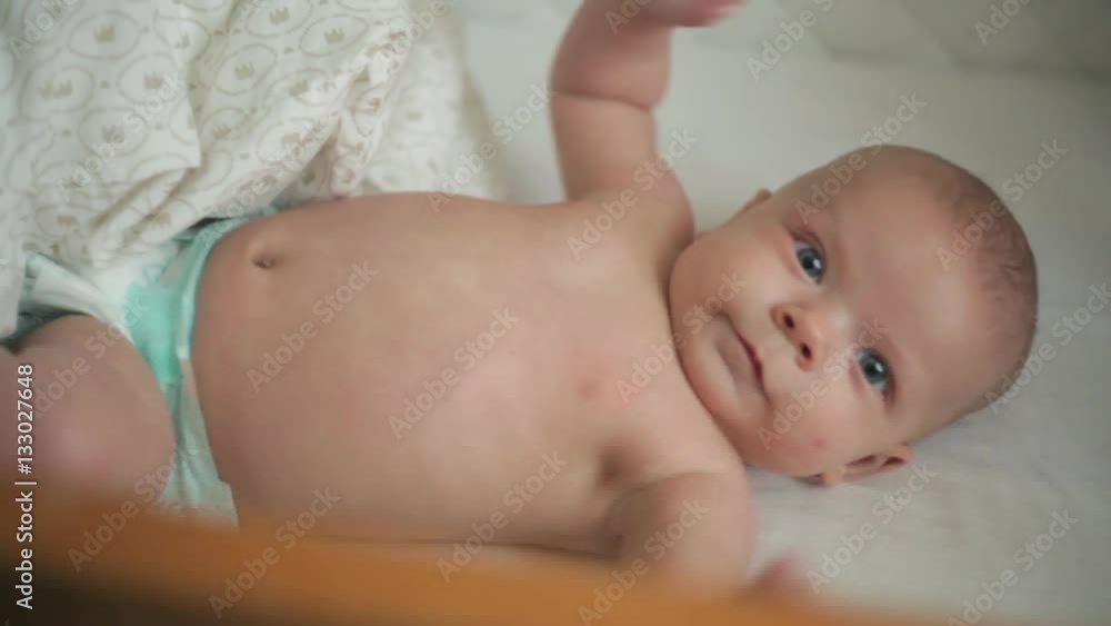 Happy newborn baby yawns closeup in white bed Happy newborn baby yawns closeup in white bed
