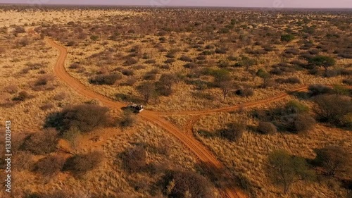 hunters traveling by jeep across the savannah in search of prey