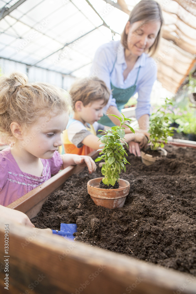 Female gardener and children in greenhouse