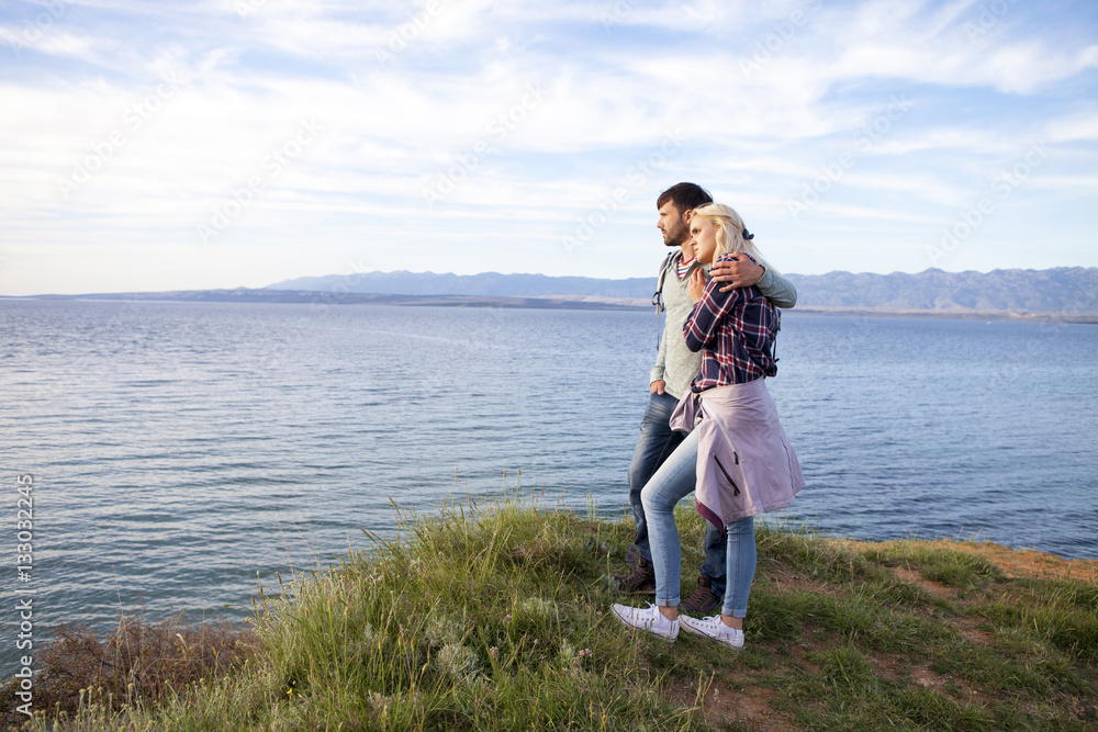 Young couple on cliff looking at sea Young couple on cliff looking at sea