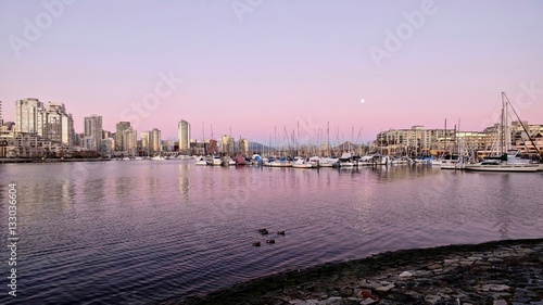 Pink sunset and full moon over boat marina. View of False Creek and Yaletown from Kitsilano. Vancouver. British Columbia. Canada.