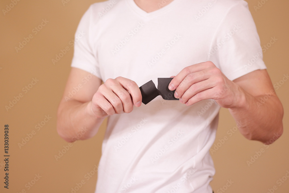 Fototapeta premium Man tearing a piece of paper in half blank black flyer brochure