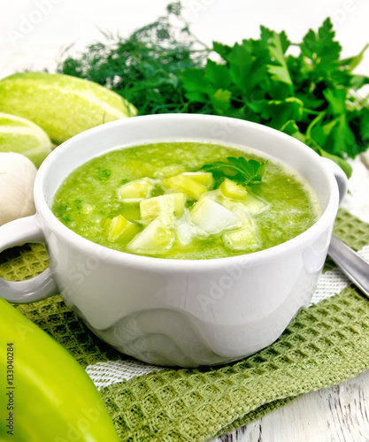 Soup cucumber with parsley in white bowl on board