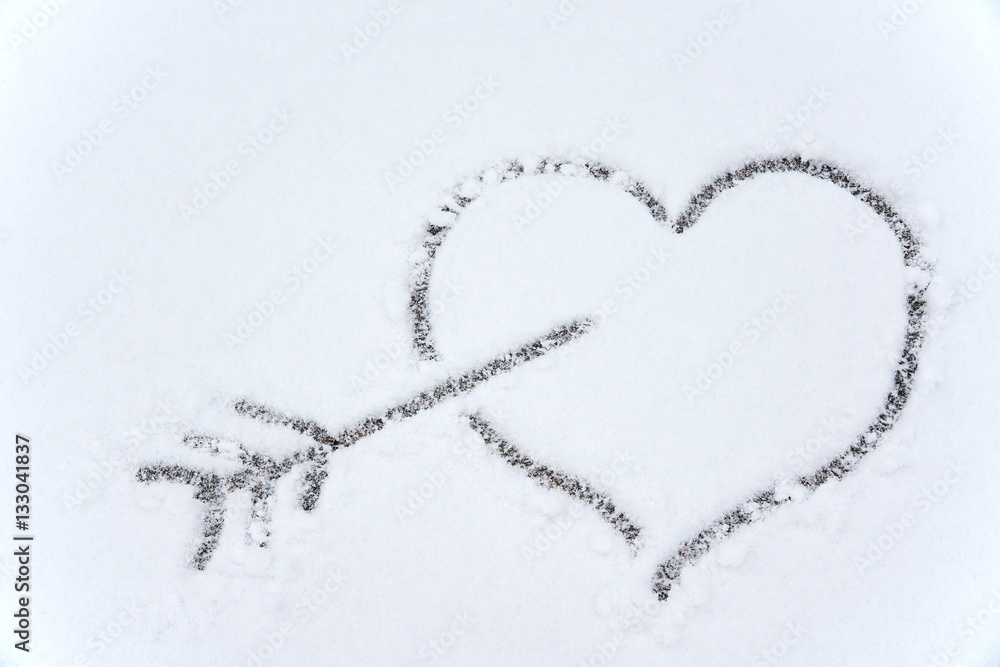 drawing heart and arrow on white snow background