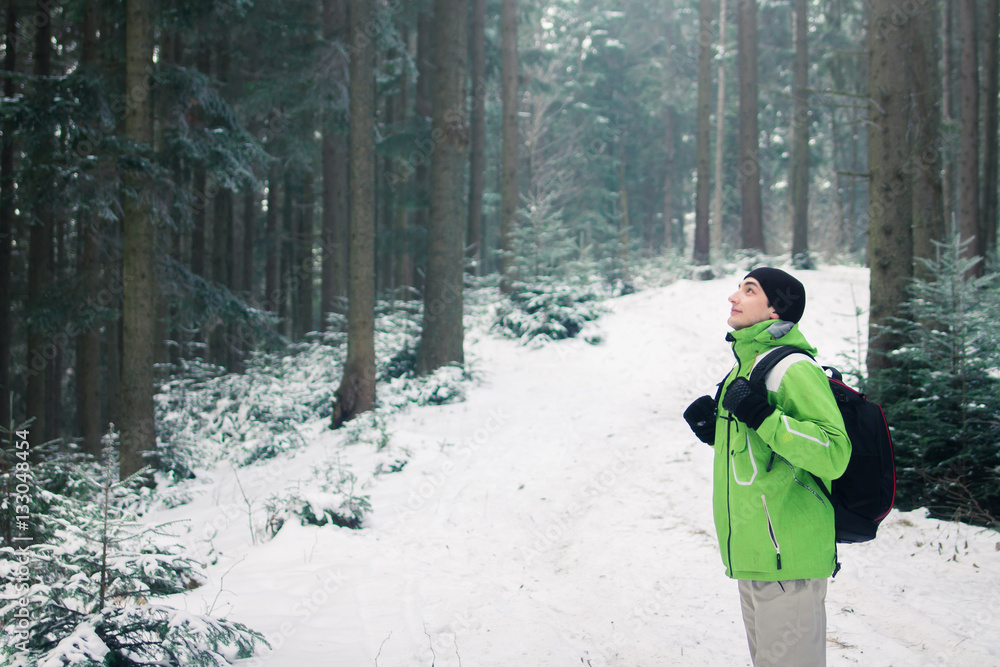 Man backpacker walking in winter mountain forest