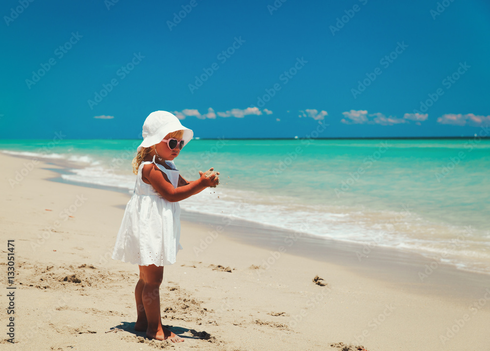 cute little girl play with sand on beach