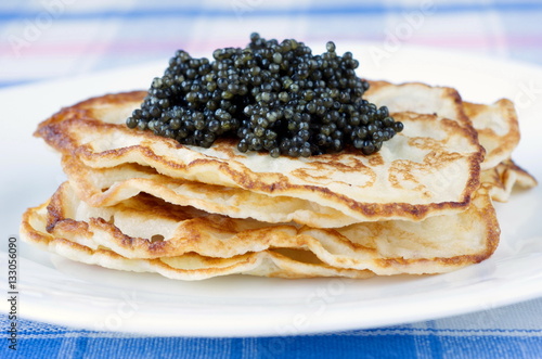 Pancakes with black caviar on plate