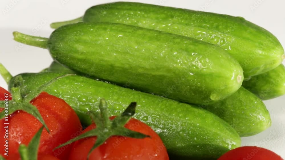 cherry tomatoes and cucumbers on a white background in drops of water cherry tomatoes and cucumbers on a white background in drops of water