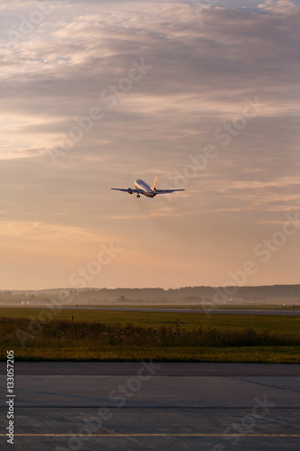 Airplane taking off at the sunset sky
