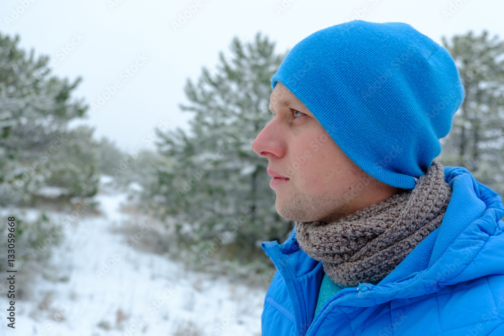 young man in a blue hat and jacket among the snow-covered forest young man in a blue hat and jacket among the snow-covered forest