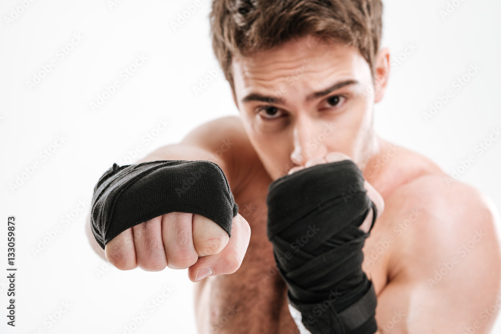 Serious young man boxer make boxing exercises Serious young man boxer make boxing exercises