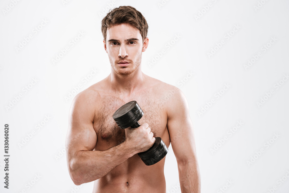 Handsome sportsman standing with dumbbell in gym