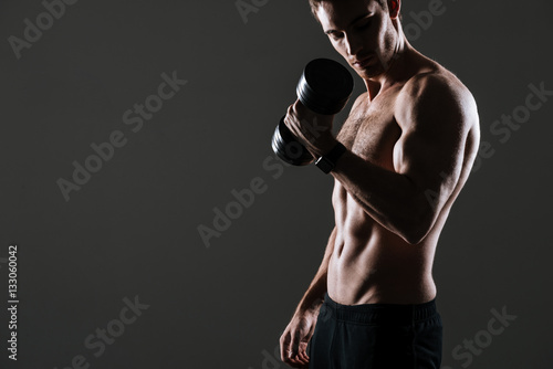Handsome athlete standing with dumbbell