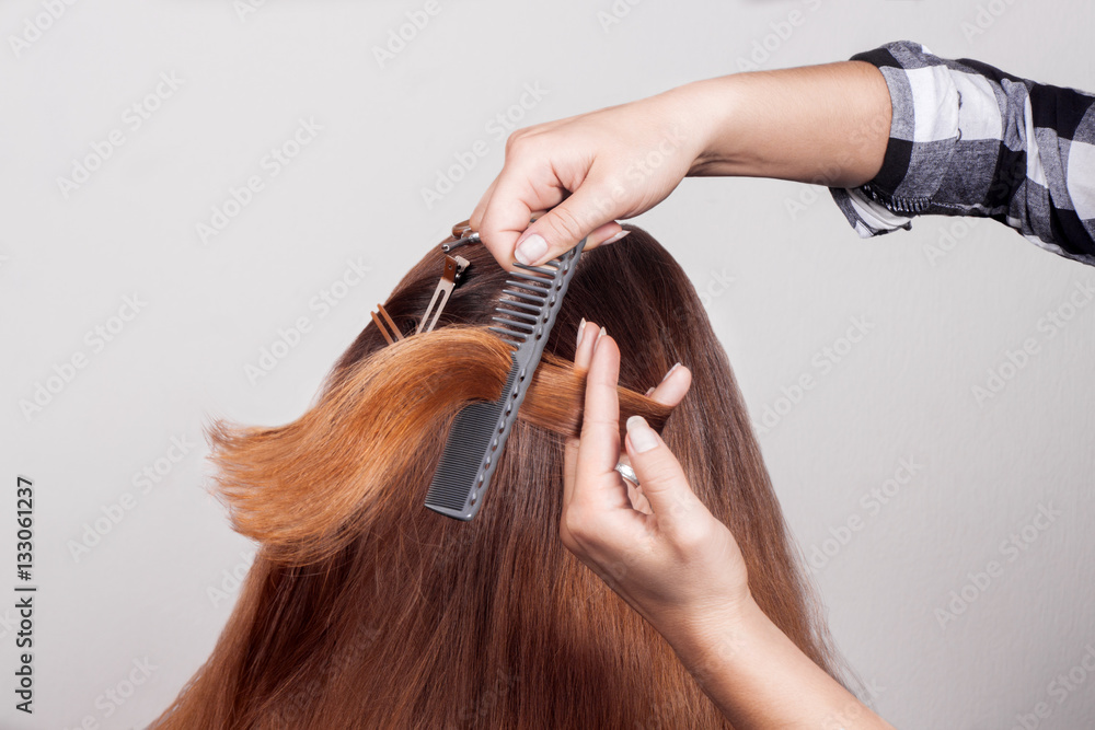 Fototapeta premium Hairdresser combing brown-haired person holding scissors in hand