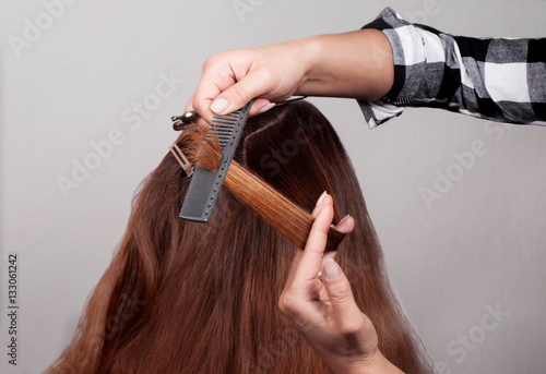 Hairdresser combing brown-haired person holding scissors in hand