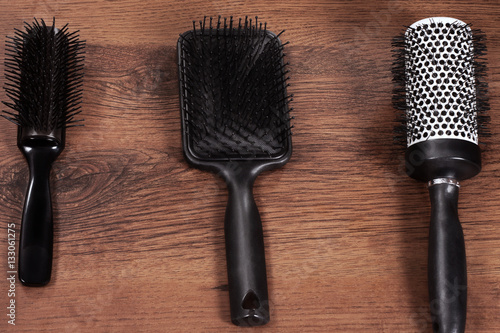 3 black  hair brushes on wood background