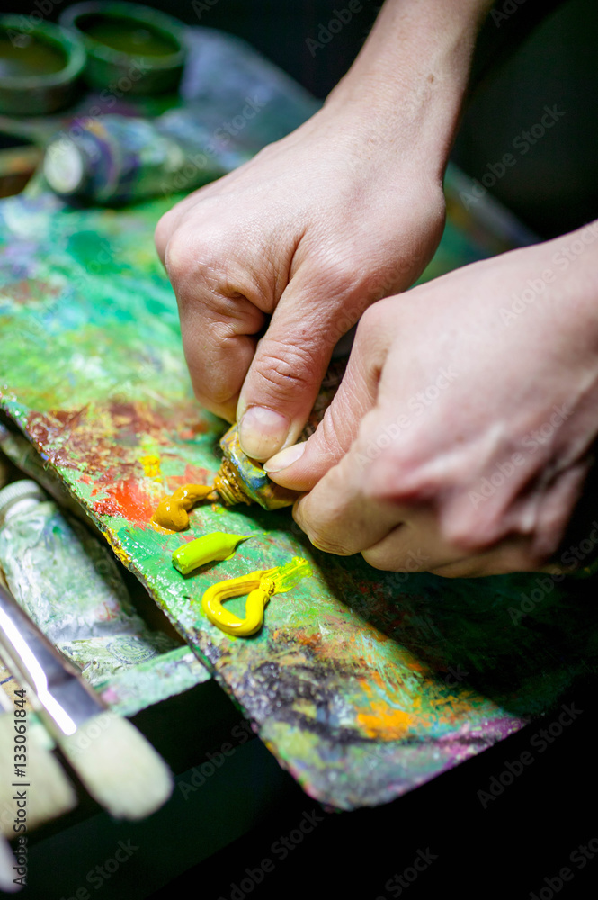 hands of artist mix paints on a palette. composition on a dark background hands of artist mix paints on a palette. composition on a dark background