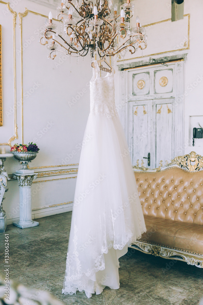 Wedding dress on the chandelier. Morning of the bride