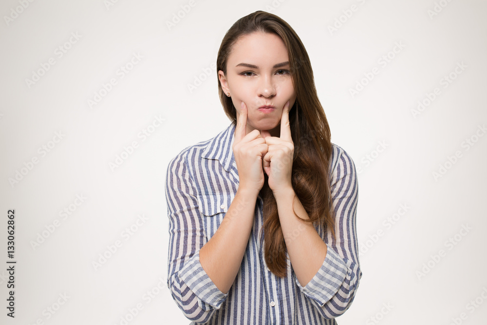 girl pointing fingers on her cheeks isolated girl pointing fingers on her cheeks isolated