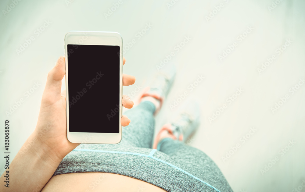 © Rasulov - Young woman is using a fitness app on her smartphone after a workout. © Rasulov - Young woman is using a fitness app on her smartphone after a workout.