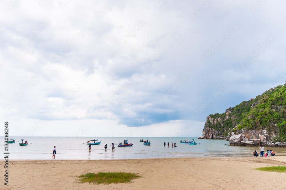 People Walking on the Beach with Cloudy Sky and Mountain.