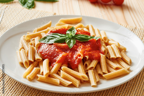 Pasta with tomato sauce and basil on white dish