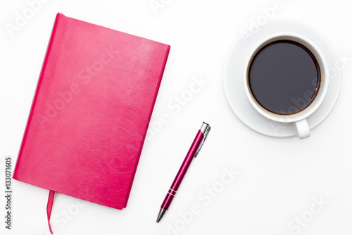 pink notebook with pen and a Cup of black coffee on white background. business minimal concept for women. Flat lay, top view.