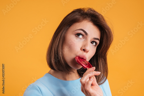 Thoughtful attractive young woman thinking and eating lollipop