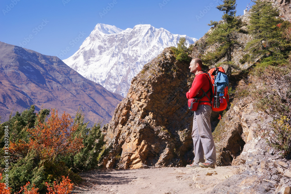 Tourist, white man, caucasian, adult, photographer, looks at beautiful Nepalese mountain landscape on trekking trail, Annapurna circuit trek in Annapurna Himal, Himalayas, Nepal, Asia. Horizontal view