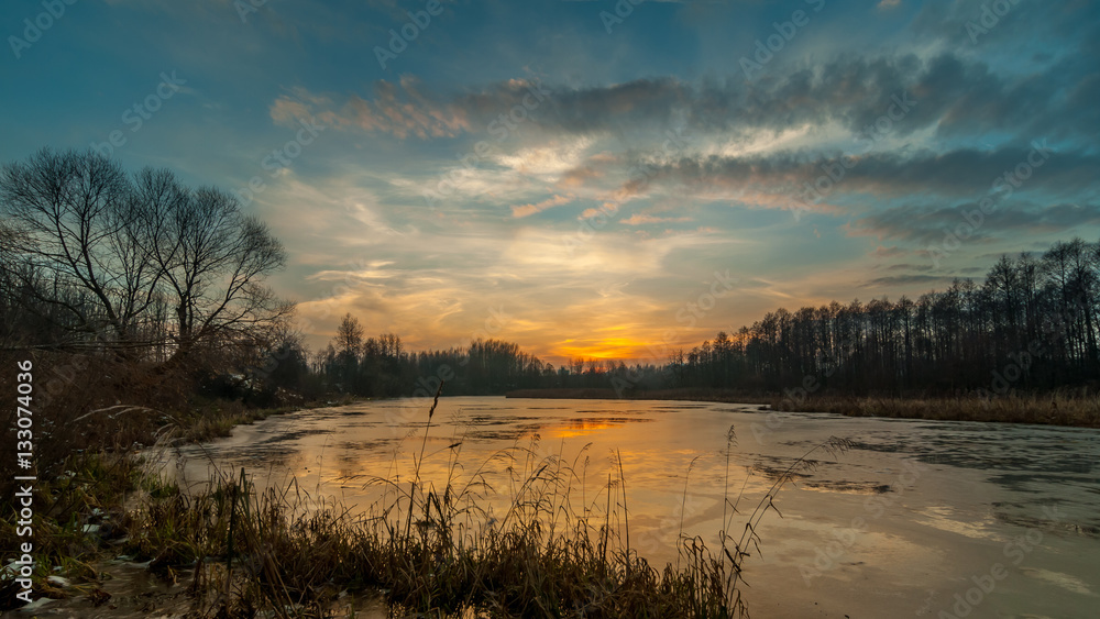 mysterious sunset over the freezing lake late autumn. landscape