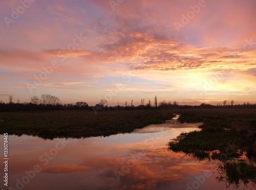 Dramatic sunset over the Widbrook stream near Cookham, Berkshire, with clouds reflected in the calm waters of the stream