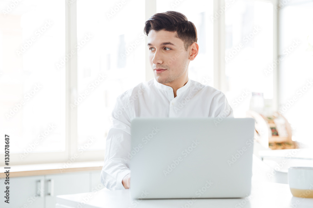 Handsome man dressed in white shirt using laptop Handsome man dressed in white shirt using laptop