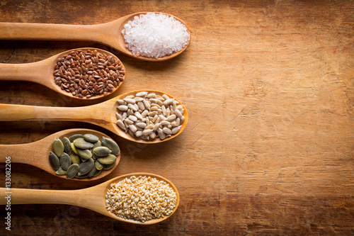 Food ingredients in wooden spoon on wooden background. Flax, pumpkin seed, sunflower seed, sesame and himalayan salt