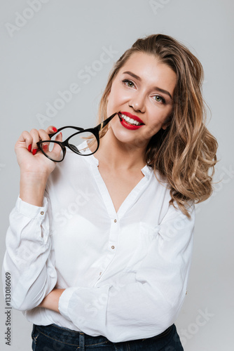 Smiling woman holding glasses and looking at camera