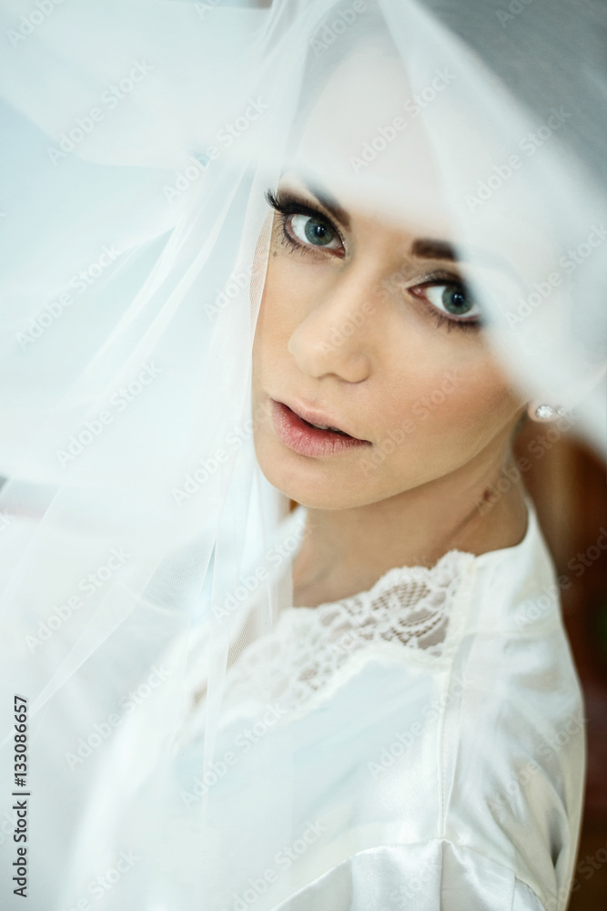 Piercing glance of stunning bride covered with veil