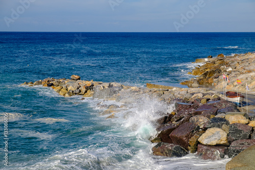 Deiva Marina rocky shore with crystal waves, Liguria, Italy.