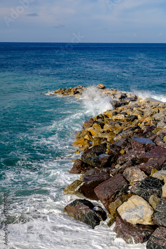 Deiva Marina rocky shore with crystal waves, Liguria, Italy. photo