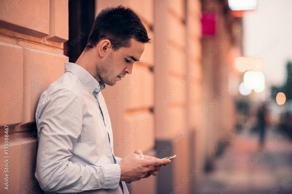Handsome young man text messaging on a city street Handsome young man text messaging on a city street