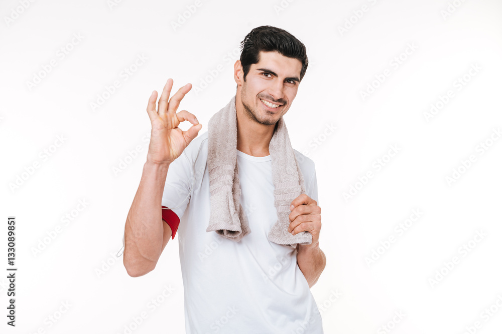 Young smiling fitness man with towel showing okay gesture Young smiling fitness man with towel showing okay gesture